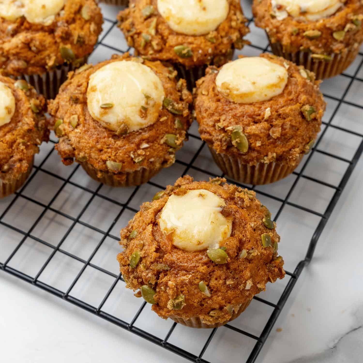 pumpkin muffins with cream cheese filling, cooling on a wire rack.