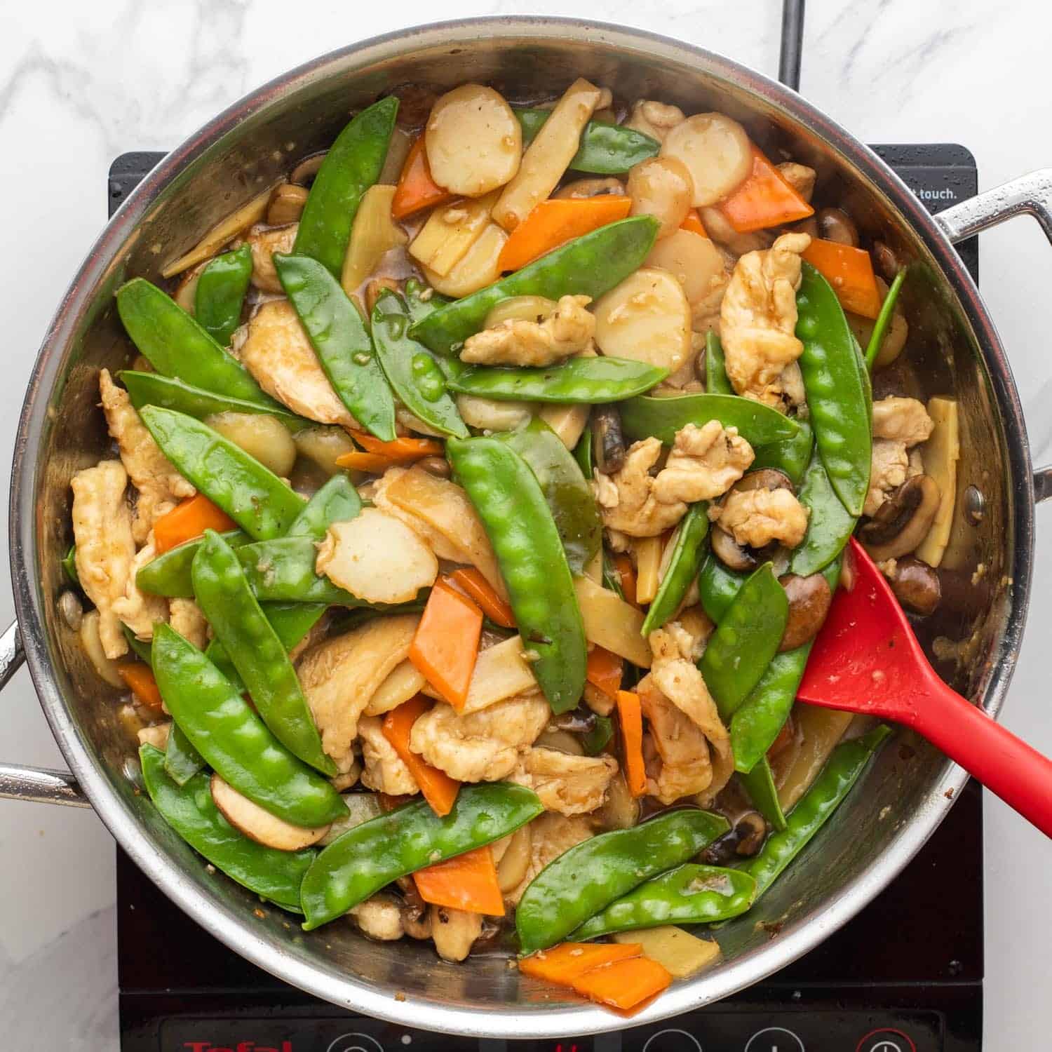 a stir fry with veggies and chicken in a large saute pan.