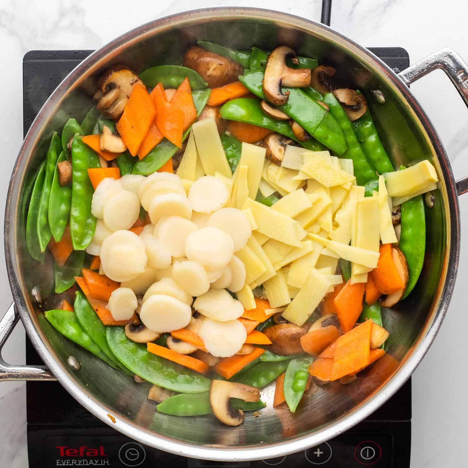 water chestnuts and bamboo shoots added to sauteed veggies in a skillet.