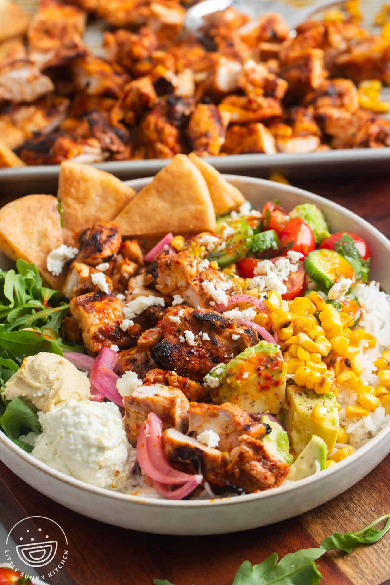 a copycat cava bowl with harissa chicken, pita wedges, and rice. 