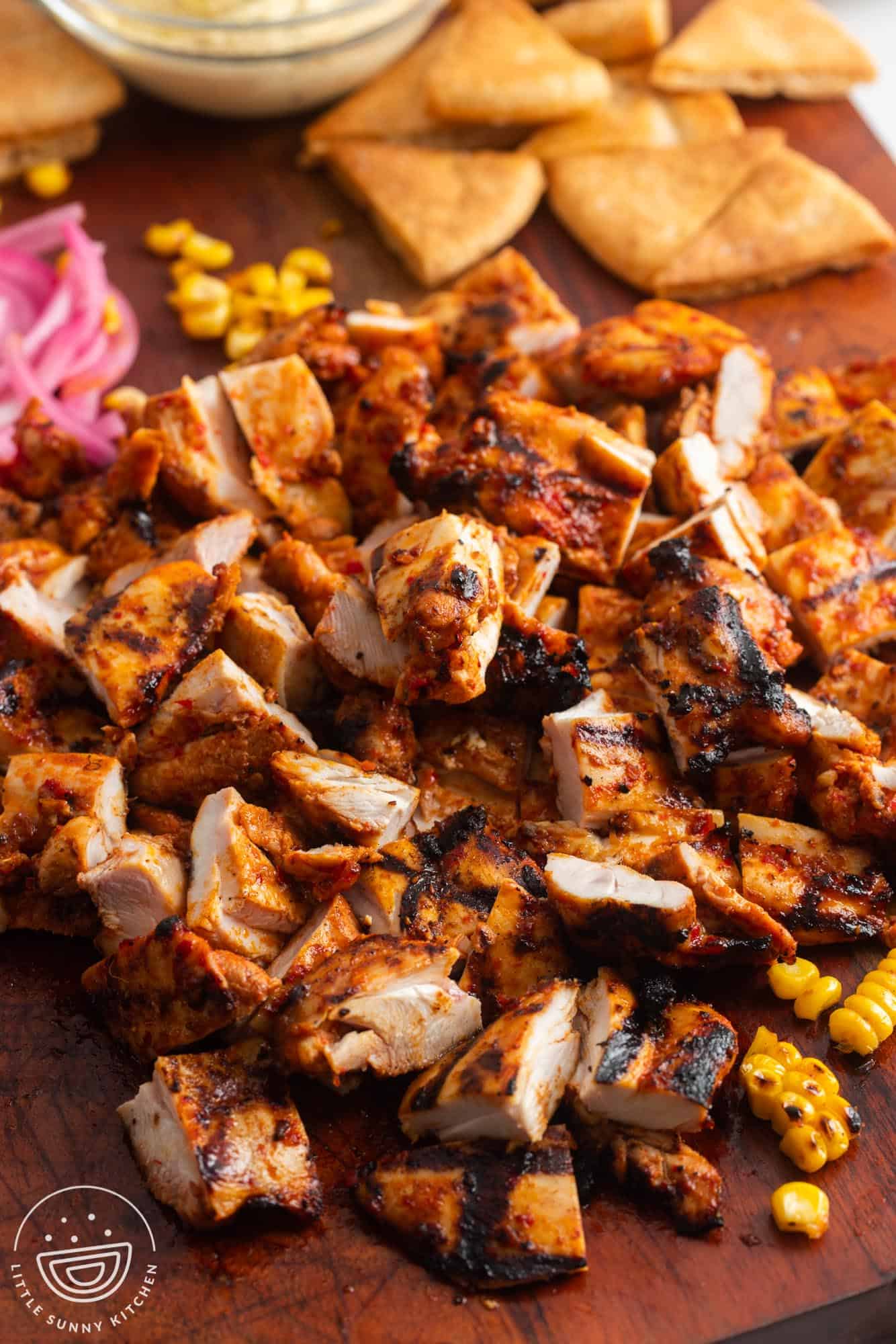 Harissa chicken cut into small pieces on a cutting board. 