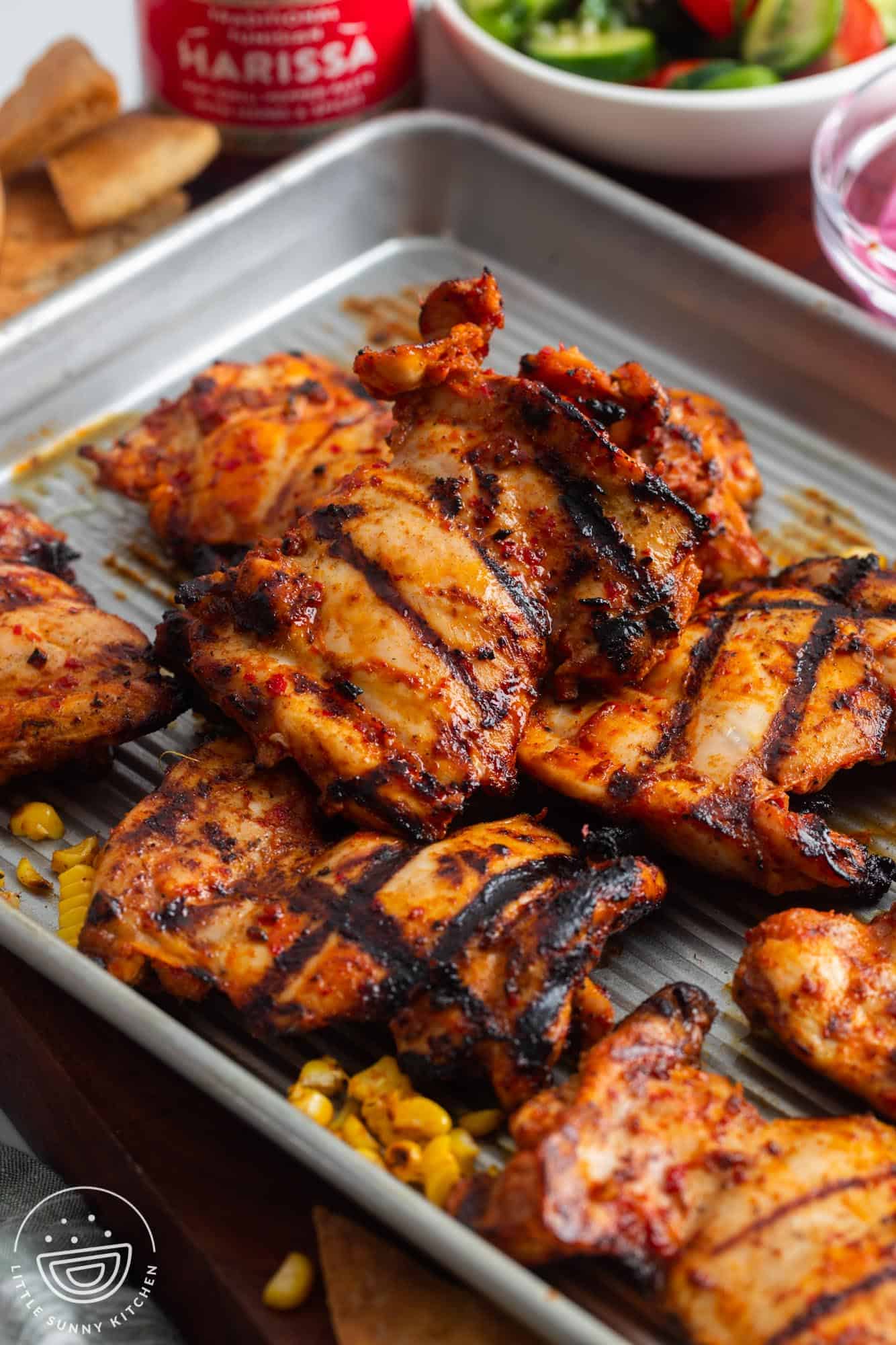 grilled harissa chicken resting on a sheet pan. 